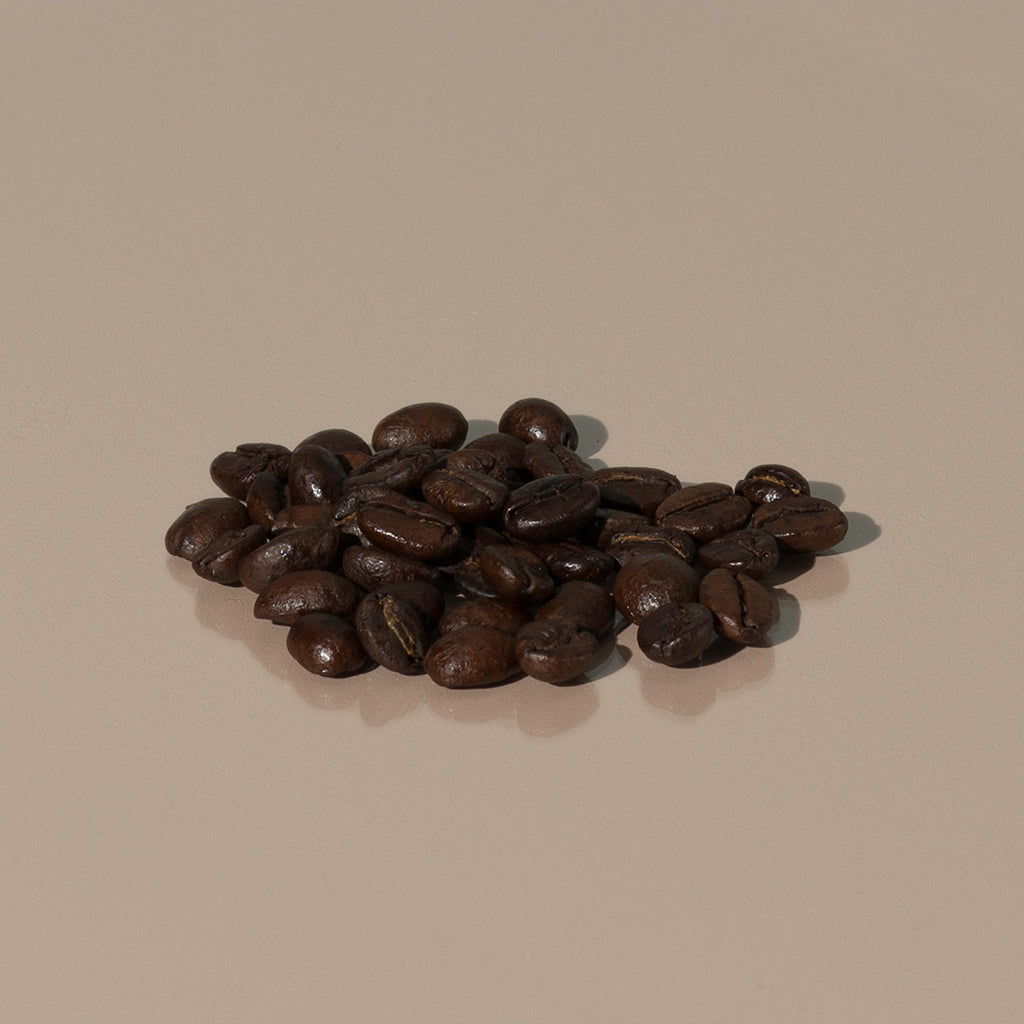 Emporium Espresso Blend by Cafellini small amount of dark brown roasted coffee grains on a table