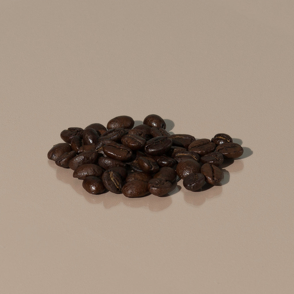 Emporium Espresso Blend by Cafellini small amount of dark brown roasted coffee grains on a table