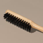 Details Close up of Groom black boar bristles beard or hair brush with idled clear beech wood handle