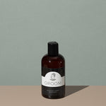 Groom beard shampoo in a amber plastic round bottle with a black clip cap and a black and white labeling with a mustache man logo