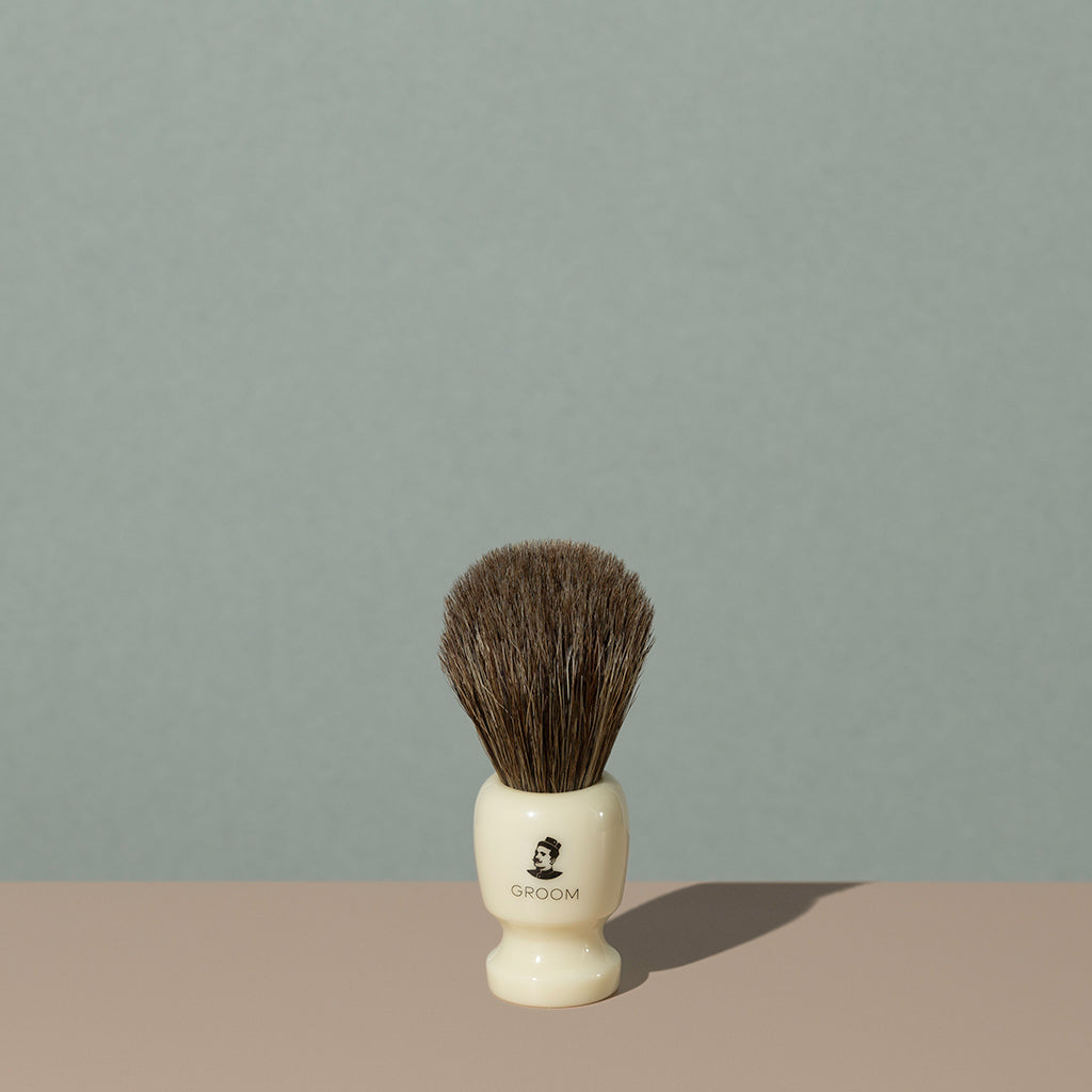 Groom shaving brush with brown horsehair bristles and cream off white acetate handle with black mustache man logo