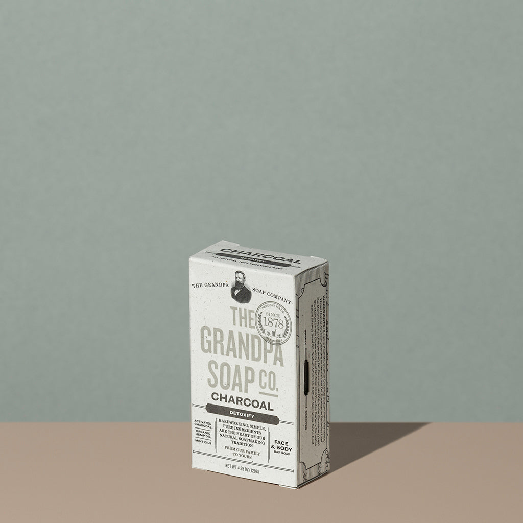 The Grandpa soap Co Charcoal soap bar in a square rectangle light gray cardboard packaging with charcoal writings