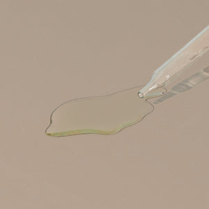 Hudson Made co beard and shave oil juniper myrrh transparent liquid spread on a table with glass dropper cap
