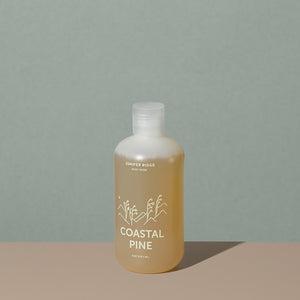 Juniper Ridge coastal pine body wash in an all clear cylindric plastic bottle with a flip top dispenser cap and white labelling of mountains and brand name