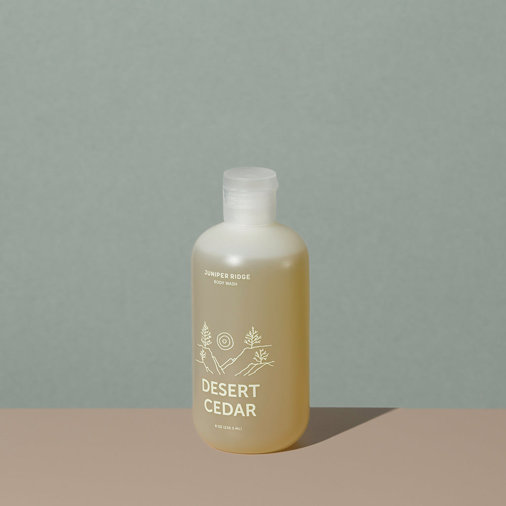 Juniper Ridge desert cedar body wash in an all clear cylindric plastic bottle with a flip top dispenser cap and white labelling of mountain and brand name