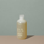 Juniper Ridge desert cedar body wash in an all clear cylindric plastic bottle with a flip top dispenser cap and white labelling of mountain and brand name