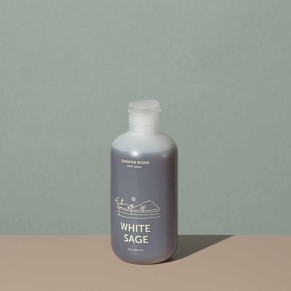 Juniper Ridge White Sage body wash in an all clear cylindric plastic bottle with a flip top dispenser cap and white labelling of mountain and brand name