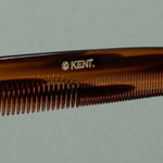 Close up details of tortoise Kent fine coarse handcrafted 190mm acetate rounded tooth comb for hair or beard with gold label on a table
