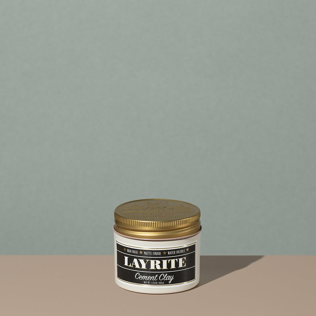 Layrite 4.25oz Cement Clay Extreme Hold and Matte Finish hair pomade in a rounded white plastic container with gold twist cap and black label