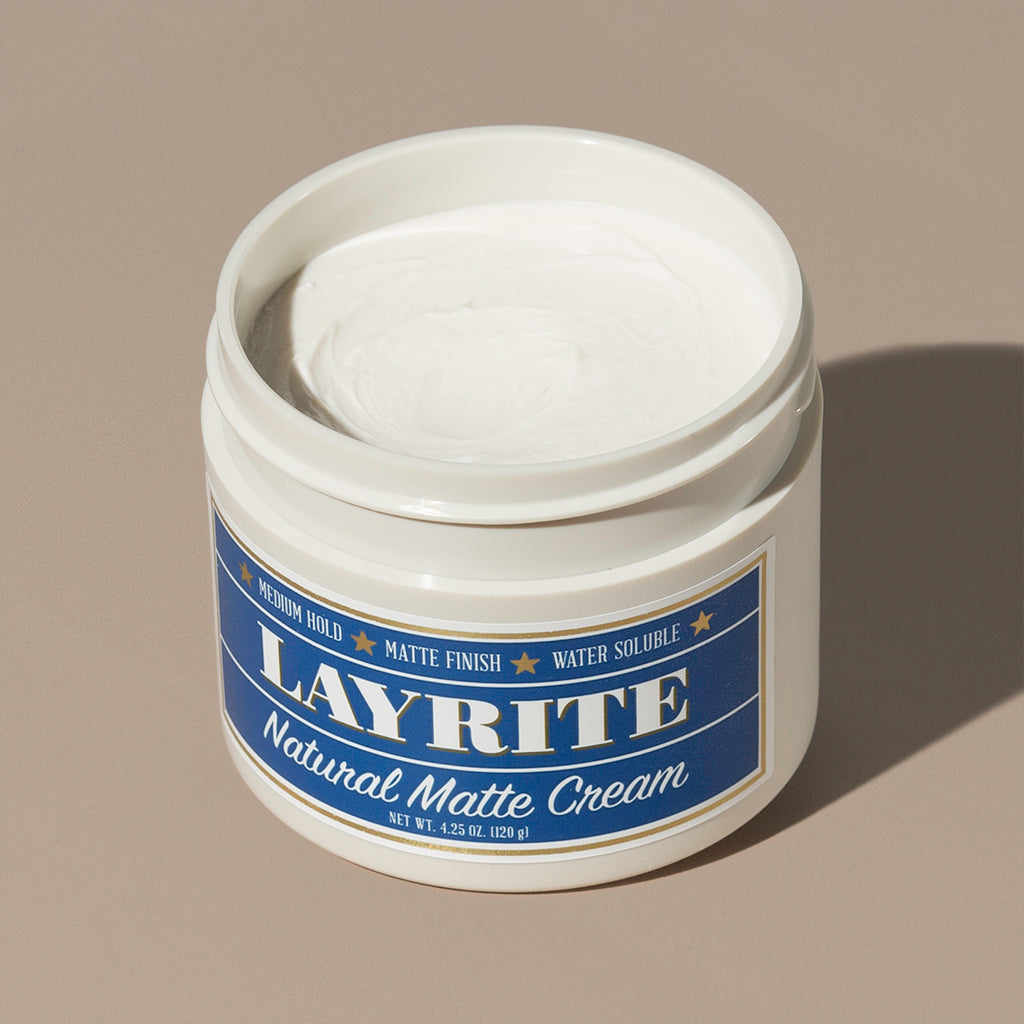 View inside white cream wax Layrite 4.25oz Natural Matte Cream Medium Hold & Natural Finish hair pomade in a rounded white plastic container with gold twist cap and blue label