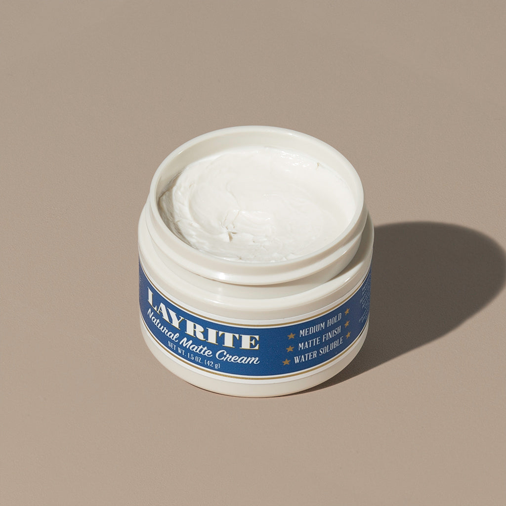 View inside white cream wax Layrite 1.5oz Natural Matte Cream Medium Hold & Natural Finish hair pomade in a rounded white plastic container with gold twist cap and blue label