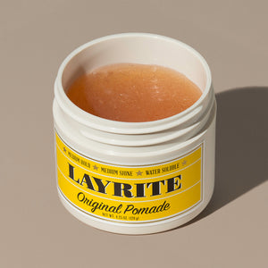 View inside transparent brown wax gel Layrite 4.25oz Original Pomade Medium Hold & Medium Shine hair pomade in a rounded white plastic container with gold twist cap and yellow label