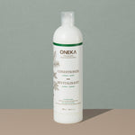 Oneka cedar and sage organic conditionner in a long cylindric clear white plastic bottle with a press cap and white and green labeling