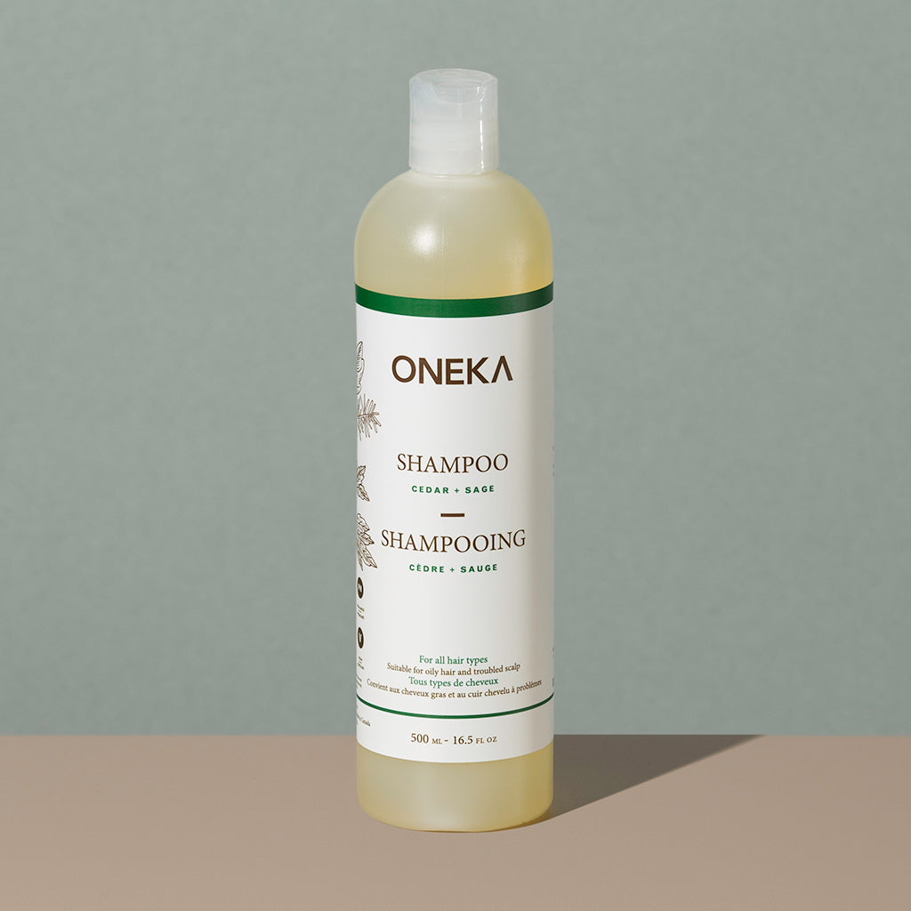 Oneka cedar and sage organic shampoo in a long cylindric clear white plastic bottle with a press cap and white and green labeling
