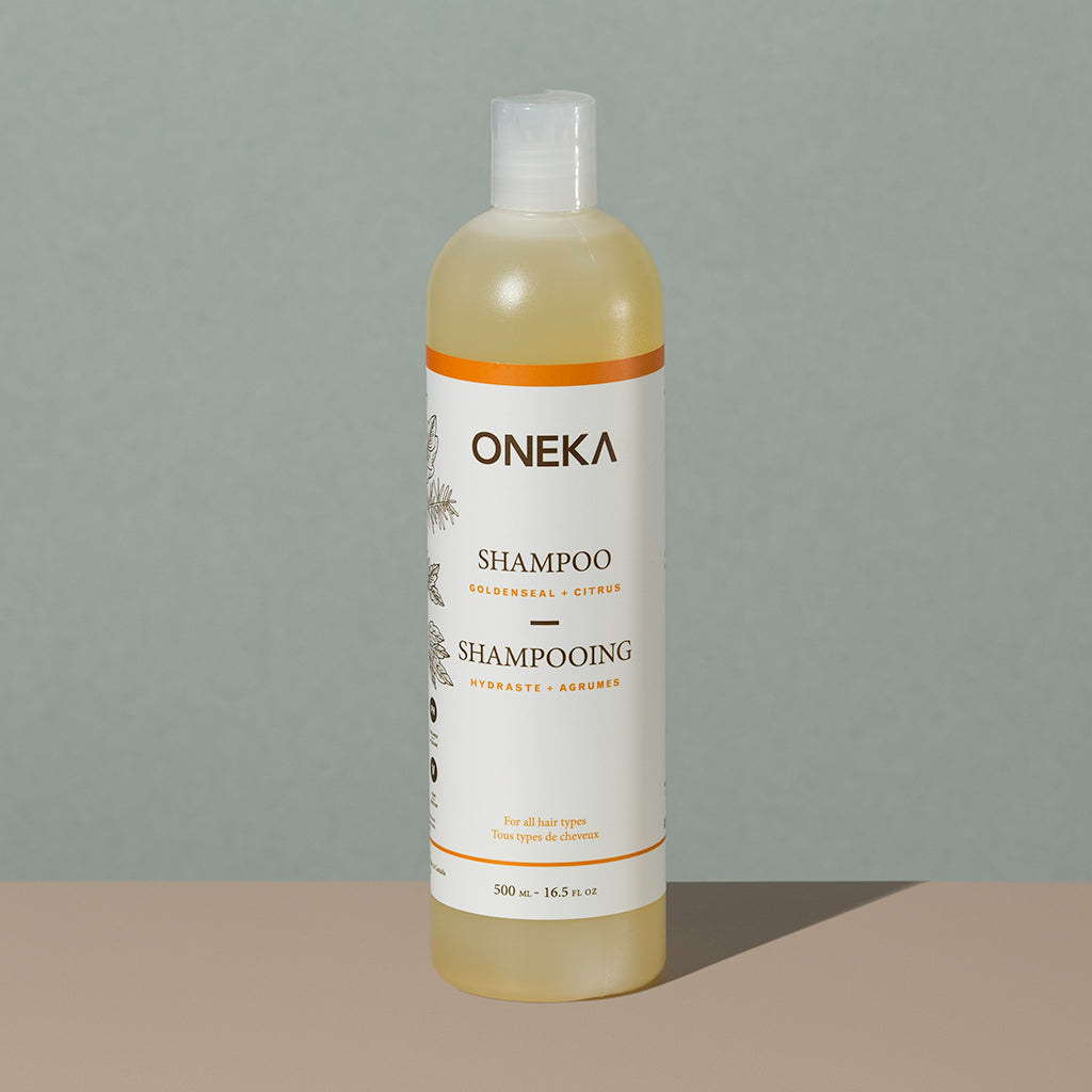 Oneka goldenseal and citrus organic shampoo in a long cylindric clear white plastic bottle with a press cap and white and orange labeling