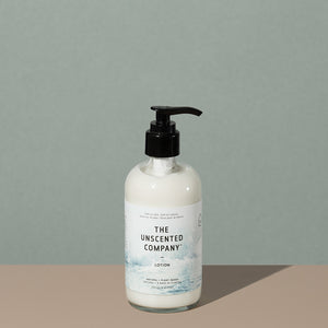 The Unscented Company Plant based hydrating lotion in a clear glass plastic bottle with a press down black dispenser cap and a white labeling with black writings and foggy gray mountains