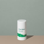 Ursa Major base layer deodorant in a white small cylindric plastic container with a cap and green labeling of mountains